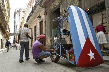 Un cubano repara su bicitaxi en una calle de La Habana